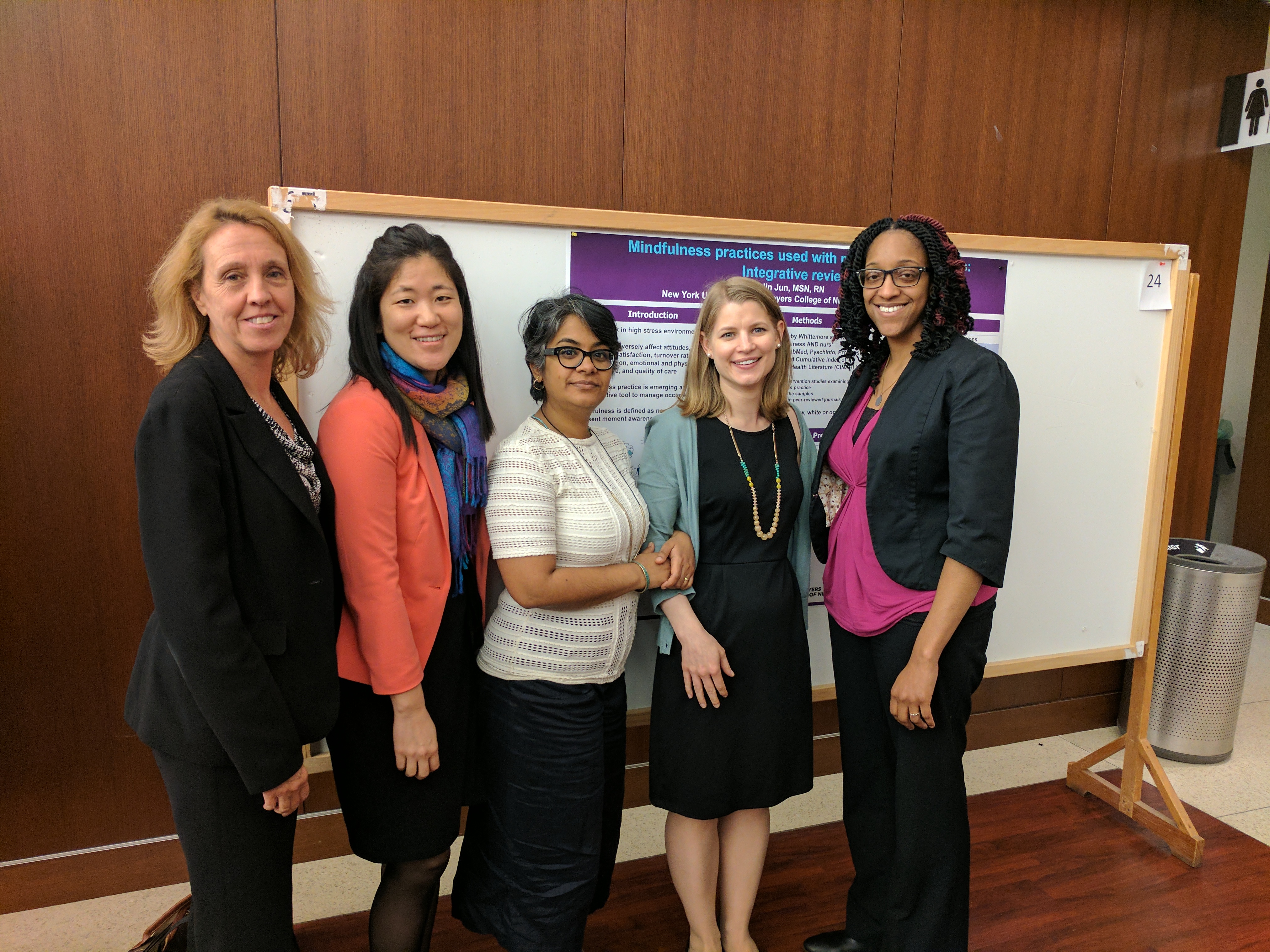 PhD Students and faculty stand in front of their poster presentation.